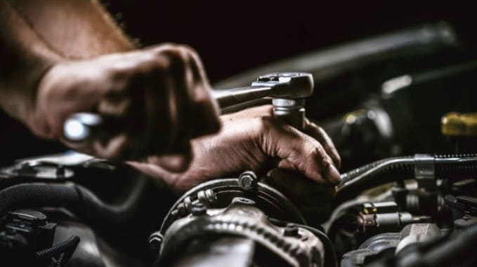 Mechaniker mit Taschenlampe bei der Arbeit am Motor